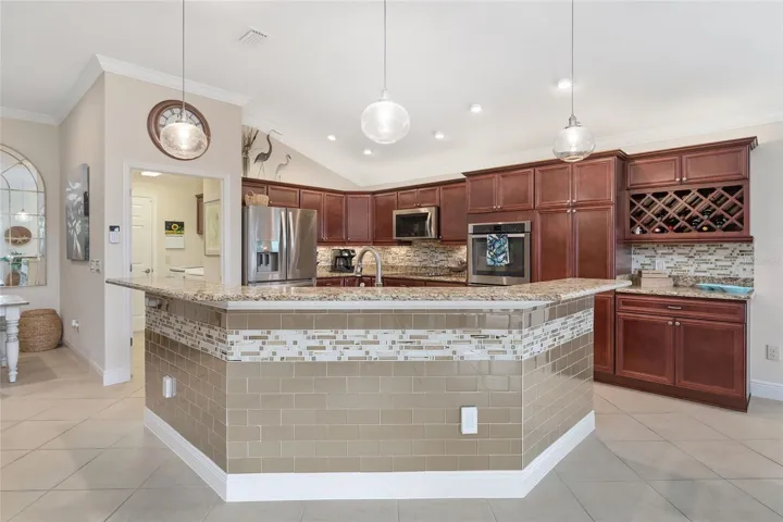 KITCHEN ISLAND HAS TILE INLAY, GRANITE SURFACE AND PENDANT LIGHTING.