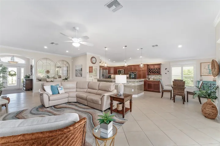 VIW FROM PRIMARY SUITE THROUGH LIVING AREA TO KITCHEN, BREAKFAST AREA, DINING AREA AND FOYER. HIGH CEILINGS WITH CROWN MOLDING, TILE SET ON DIAGONAL AND PLANTATION SHUTTERS THROUGHOUT.