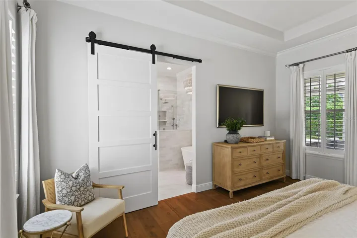 Barn door leads to renovated primary bathroom