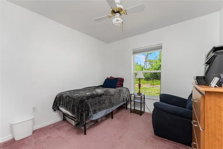 Guest bedroom #3 has carpeted flooring and ceiling fan.