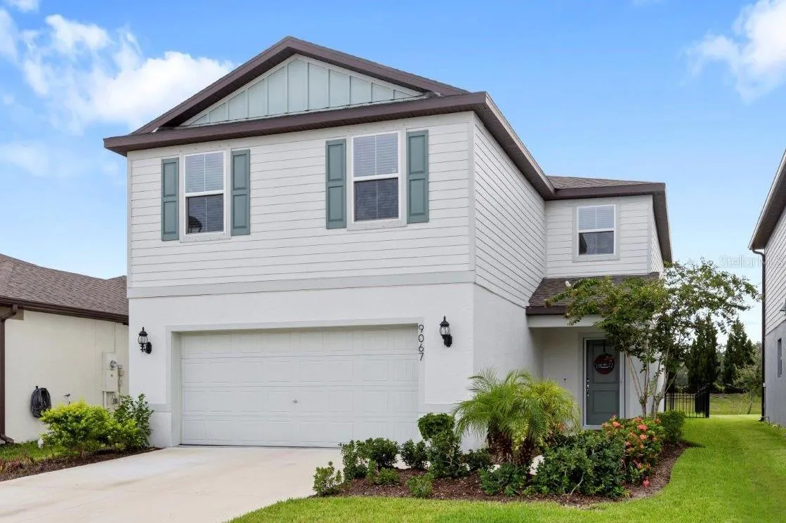 Front elevation showing the two car garage, front entry way with a storm door, and landscaping.