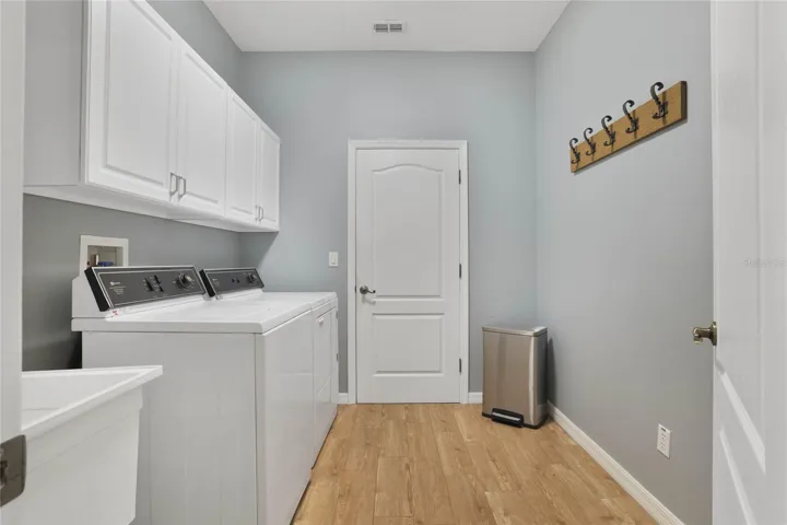 Laundry room leads to the garage and has a wash tub sink and cabinets