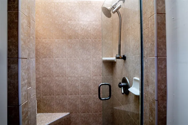 The shower area of the master bath has a corner seat, glass shower door, ceramic tile surround and quality fixtures.