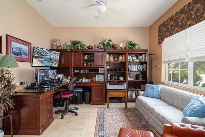 The den office has ceiling fan with light, custom window treatments, and ceramic tile flooring.