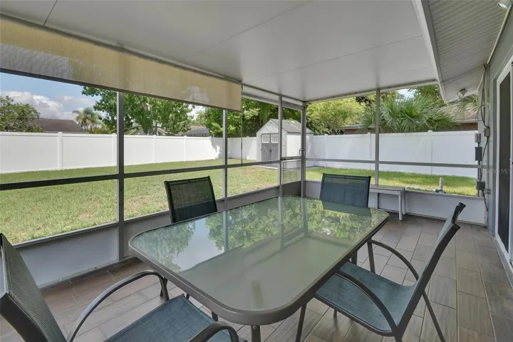Screened porch looking out over fenced backyard with shed