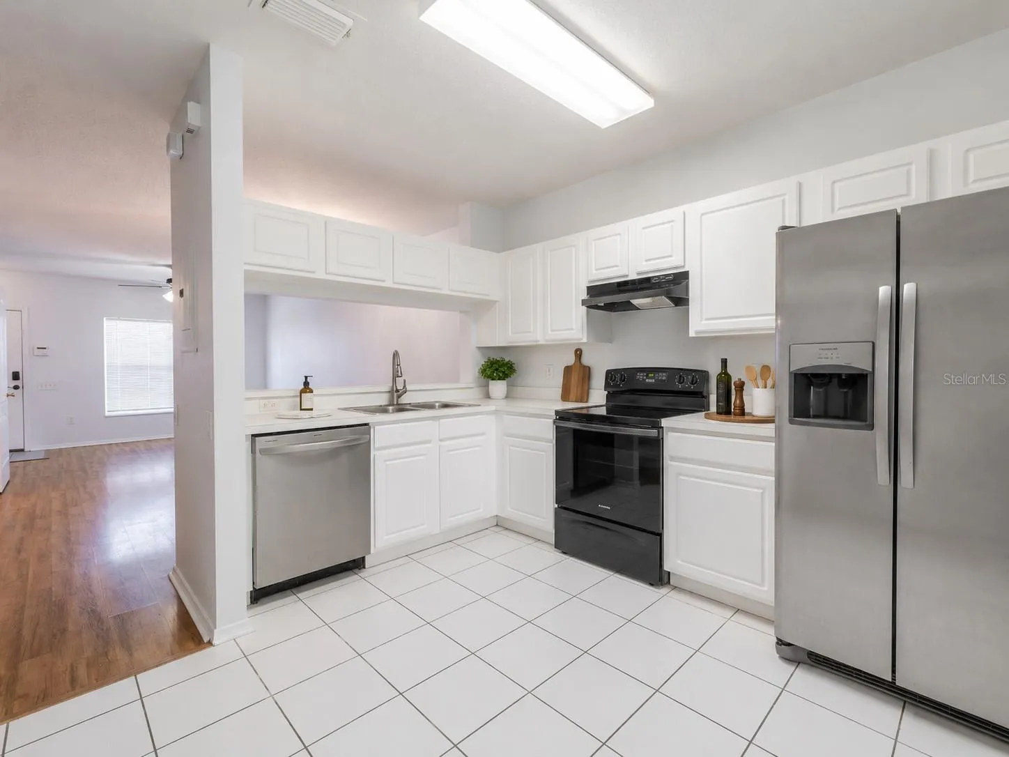 Kitchen features ceramic tile flooring, stainless steel appliances including a French door refrigerator with ice maker and water dispenser, an electric range and sliding glass door to the private screened in patio.