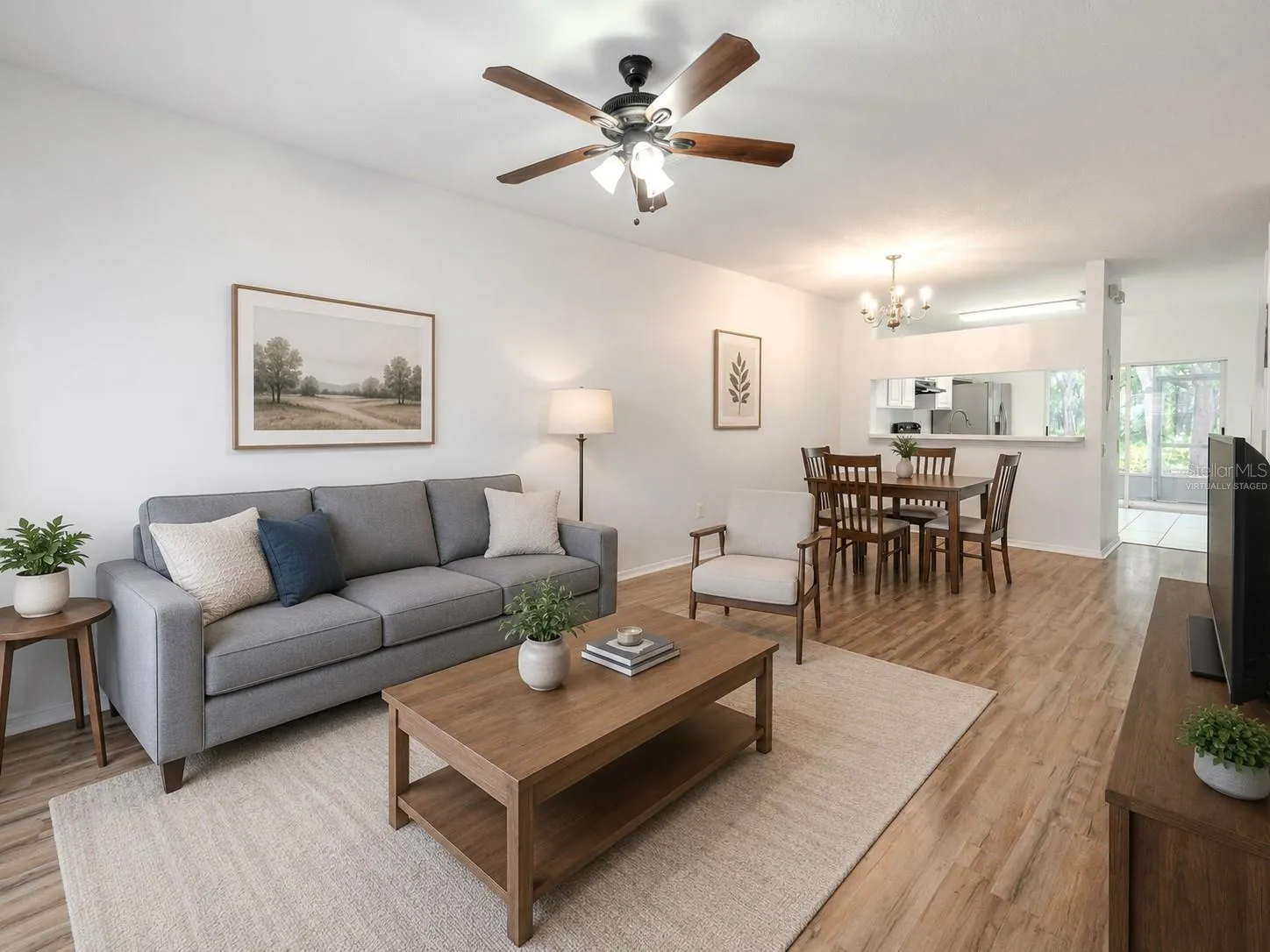 The Living room features neutral tones, wood laminate flooring, a ceiling fan with light kit and picture window. (Photo has been virtually staged.)