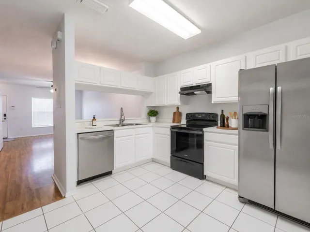 Kitchen features ceramic tile flooring, stainless steel appliances including a French door refrigerator with ice maker and water dispenser, an electric range and sliding glass door to the private screened in patio.