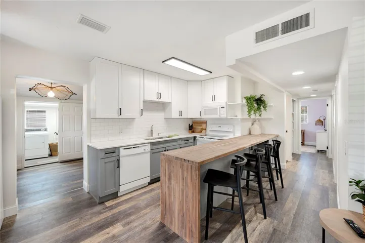 The nicely remodeled kitchen has much to offer, the Butcher block waterfall breakfast bar can accommodate the whole family and is great for entertaining .This view also features the entrance to the very large dining room and beyond that the indoor laundry room. Or to the right in the photo, the entrance to the primary suite , main bathroom and bedrooms 1 & 2.