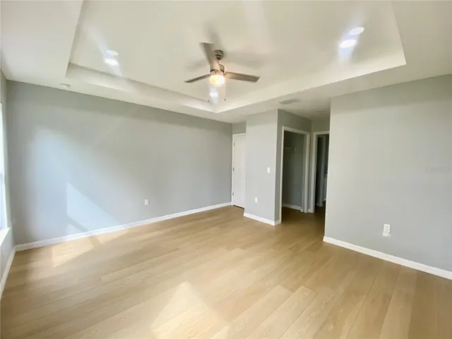 primary bedroom with trey ceiling & ceiling fan