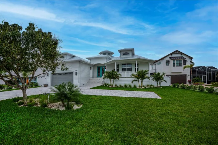 Rich paver lined driveway with extra side parking, grand open air patio, sleek  metal roof and stunning cupola gives this key west style estate a magical first impression