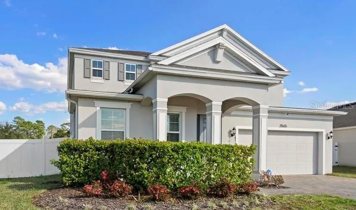 Large grand entrance with front porch, manicured lawn & paved driveway.