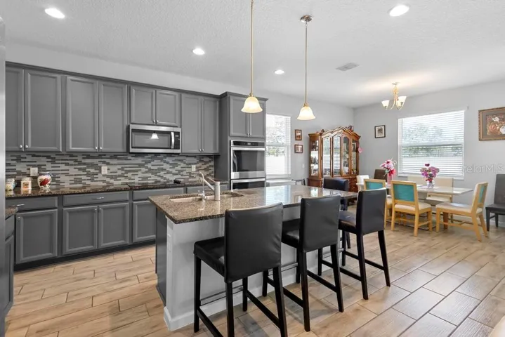 Kitchen with stone countertops,  sink built in double oven , microwave, electric stove top, walk in pantry, hd recessed lighting, natural bright and light.