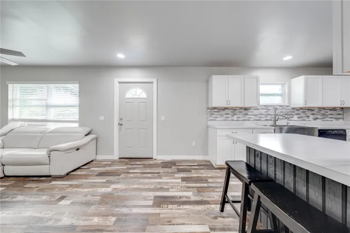 View from hallway of front door, living room and kitchen