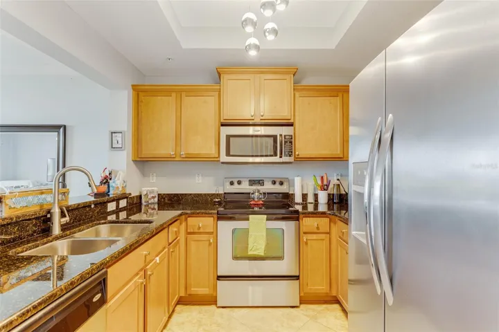 Kitchen with granite countertops, wood cabinets, newer refrigerator,