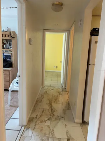 Hallway leading to bedrooms and bedroom on the left with porcelain tile flooring.