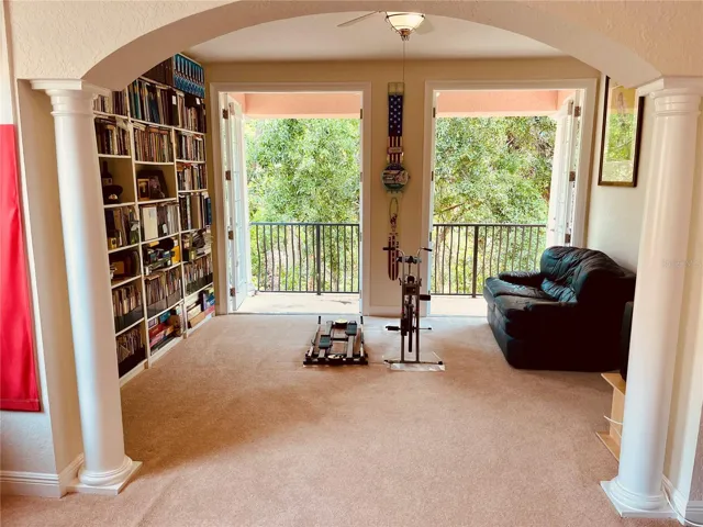 Primary bedroom through the pillars to the second bonus room and out the double French doors to the private back balcony