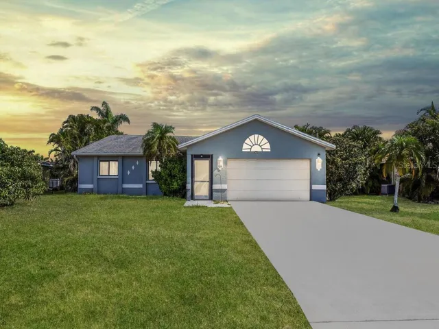 Charming front exterior with tropical landscaping, and a spacious driveway with a two-car garage.