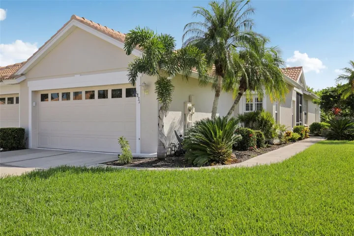 Exterior front with double garage and lush Florida landscaping.