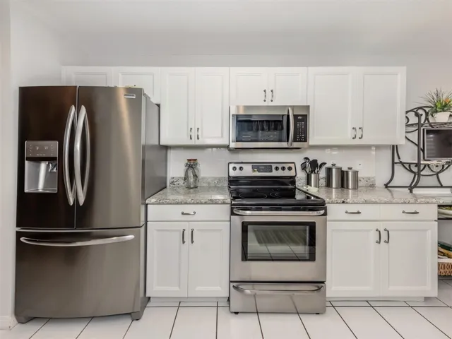 The kitchen is a chef's dream with bright white cabinets, stainless steel appliances, tasteful granite and a crisp white backsplash.