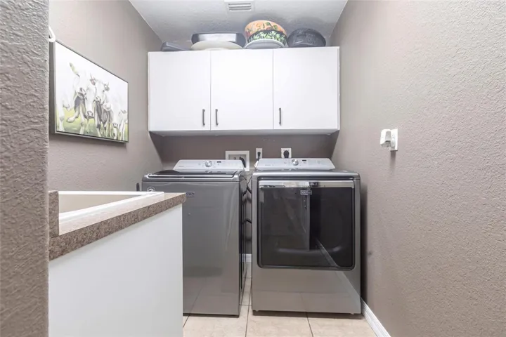 Well-organized laundry room featuring cabinetry and full-size washer and dryer.