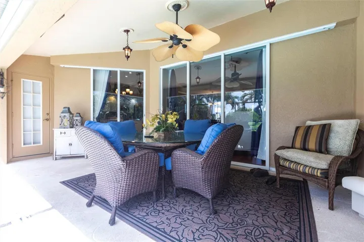 Well-appointed covered lanai offering shaded outdoor dining and lounge space, with pocketing sliding doors and convenient bath access.