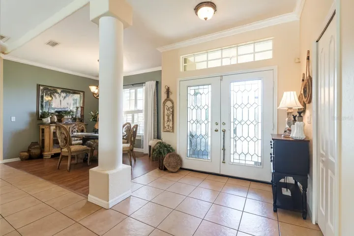 Welcoming foyer featuring glass double doors, tile floors, and architectural column.