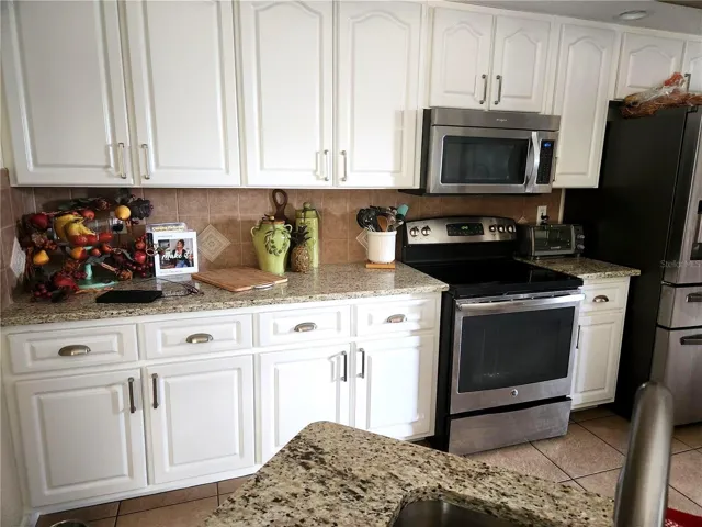 Clean, inviting kitchen with white cabinetry, granite countertops, stainless steel appliances, and generous workspace—designed for both everyday cooking and entertaining.
