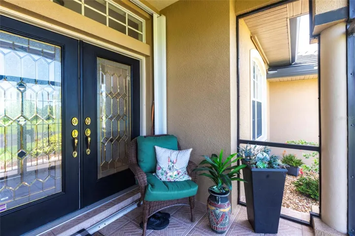 Warm and inviting front entry with decorative glass doors and private porch seating.