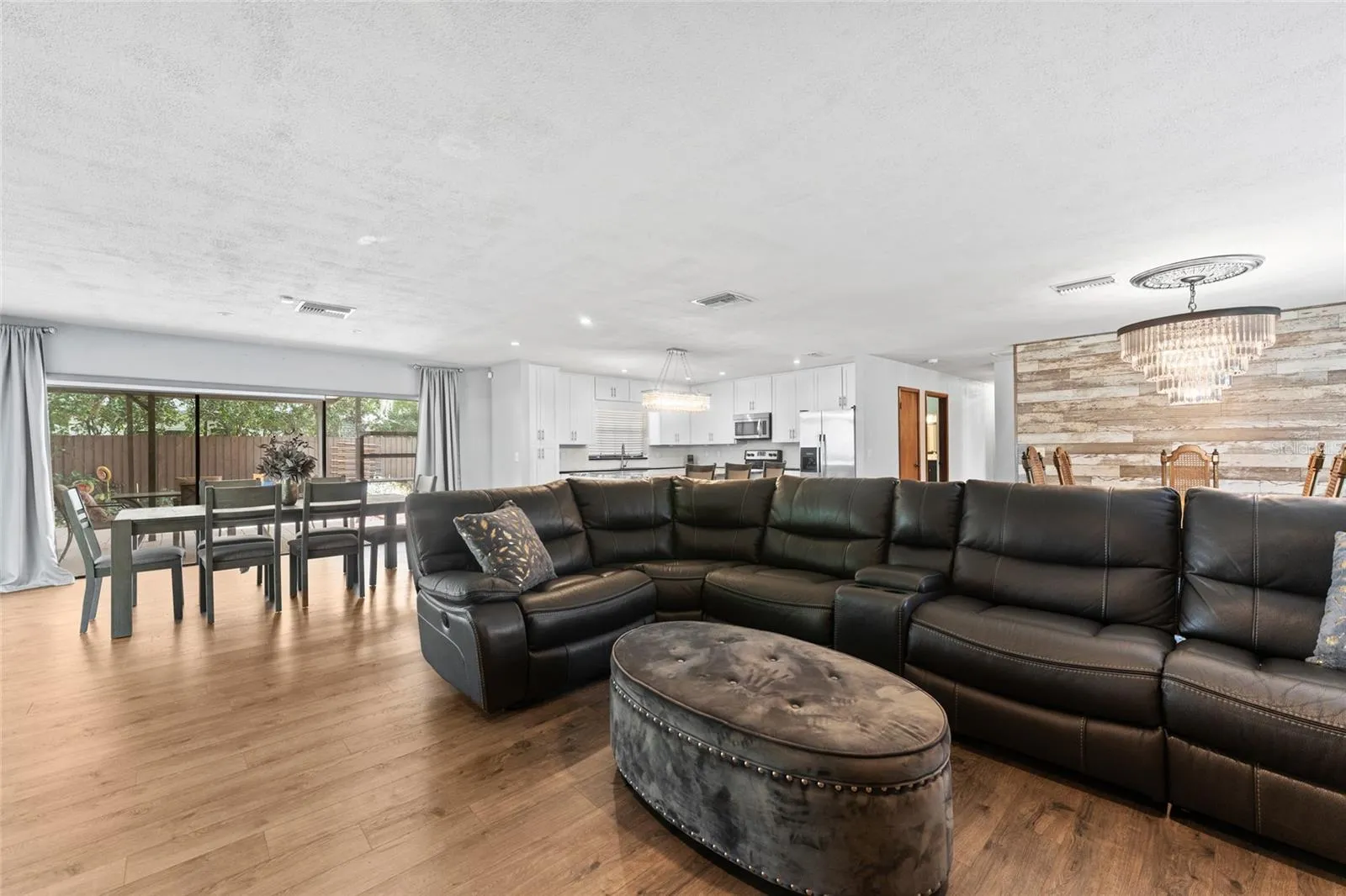 An open-concept layout is anchored by a striking floor-to-ceiling stone fireplace and wide plank wood-look flooring.