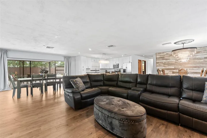 An open-concept layout is anchored by a striking floor-to-ceiling stone fireplace and wide plank wood-look flooring.