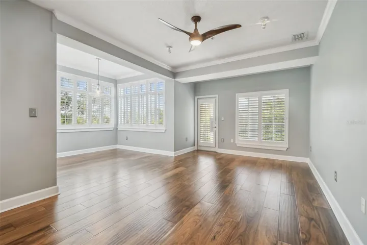 Living/dining room combination featuring engineered hardwood floors, and plantation shutters throughout.