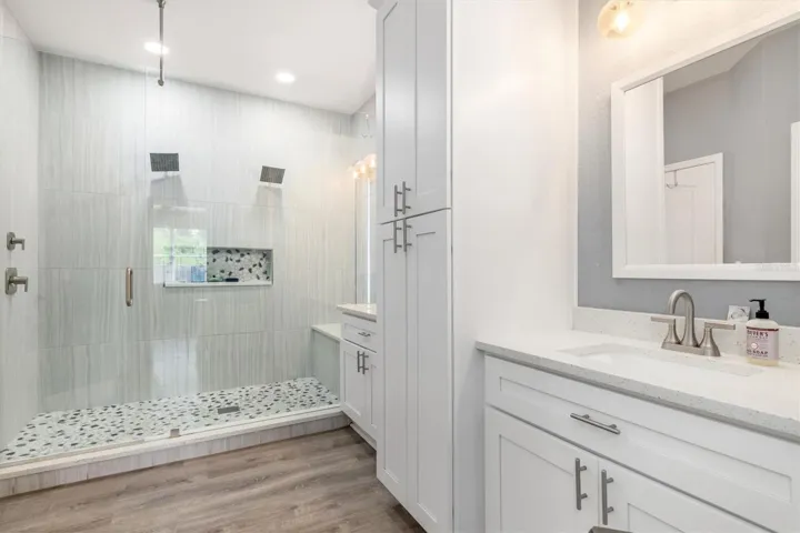 Upgraded primary bathroom with white cabinets and storage tower.