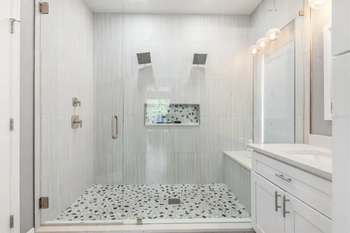 Seamless glass shower doors and double rainheads in shower.