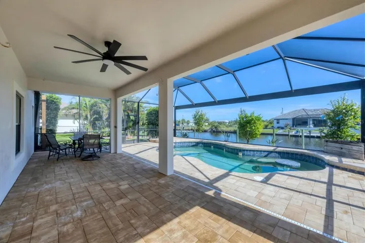 lanai and pool area is pavered as well as a paver patio outside the cage to right side leading down to dock and paver sidewalk from front drive to front door