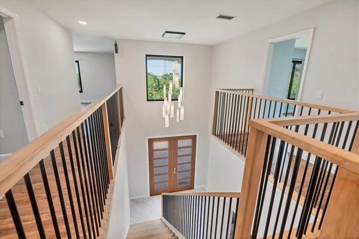 gorgeous stairway and custom designed italian light complements beautifully to your right doorway shown is bedroom 3 not show to far right corner is primary suite, left side you'll find bedroom 2, laundry, bedroom 4 and bonus room at very rear of this photos
