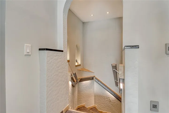 Updated well lit hallway guides you gracefully to the inviting lower level, seamlessly connecting the home’s living spaces.