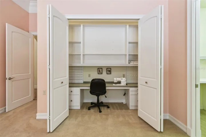 Spacious office with private half bath and direct access to the lanai. Includes a dedicated sewing area with a built-in tabletop and integrated Janome sewing machine, along with additional shelving for ample storage.