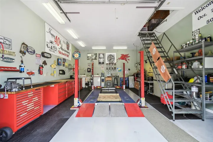 The carriage house features a spacious workshop equipped with a 7,000 lb car lift and metal stairs leading to a large attic, which includes a thermostat-controlled exhaust fan. The shop also offers Snap-on workbenches with hardwood countertops, a laundry sink, refrigerator, and washer and dryer for added convenience.