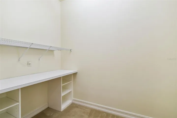 Spacious office with private half bath and direct access to the lanai. Includes a dedicated sewing area with a built-in tabletop and integrated Janome sewing machine, along with additional shelving for ample storage.