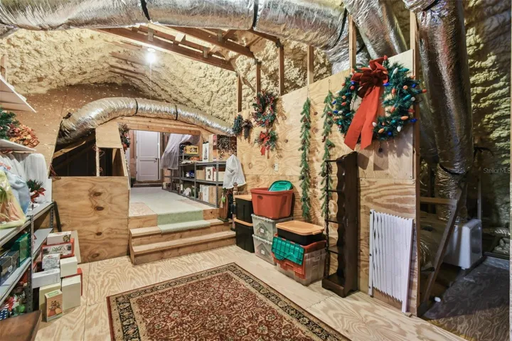 Upstairs, on either side of the guest suite and sitting room, are doorways leading to two spacious attic areas, both offering abundant storage. The attic above the garage is equipped with a 400 lb capacity electric lift, providing an easy and efficient way to move items between the garage and attic.