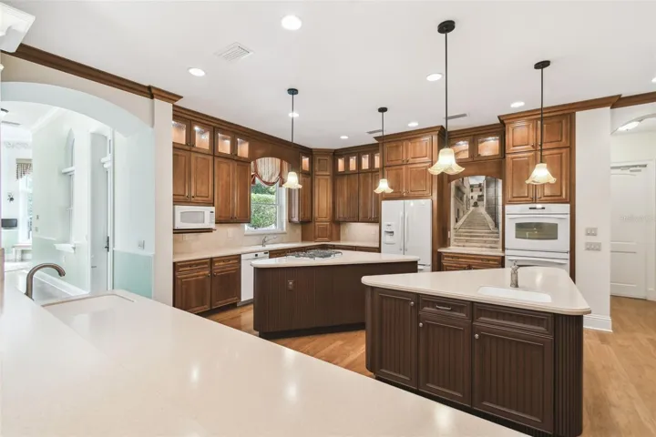 Gourmet chef’s kitchen showcases two expansive islands, three sinks, Corian countertops, custom cabinetry, a Bosch dishwasher, gas cooktop, and a separate ice maker. The adjacent butler’s pantry is perfect for entertaining, featuring a prep area, warming drawer, second refrigerator, and a spacious walk-in pantry.