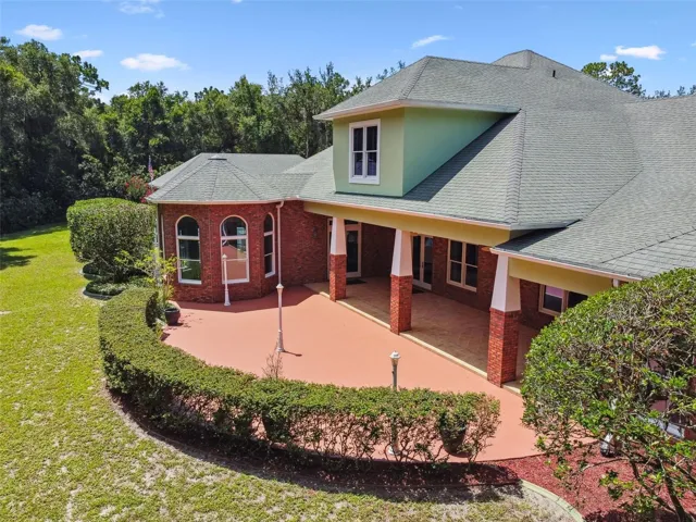Spacious lanai partially covered by a roof, featuring two ceiling fans and built-in lighting. The entire covered area showcases custom tile flooring, creating an ideal space for entertaining. Access is provided through three French doors and one additional door connecting to various rooms in the home.