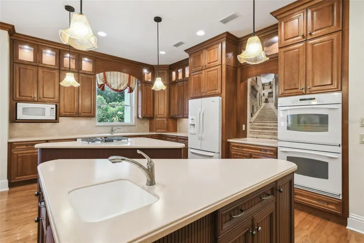 Gourmet chef’s kitchen showcases two expansive islands, three sinks, Corian countertops, custom cabinetry, a Bosch dishwasher, gas cooktop, and a separate ice maker. The adjacent butler’s pantry is perfect for entertaining, featuring a prep area, warming drawer, second refrigerator, and a spacious walk-in pantry.
