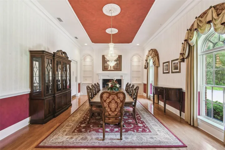 Formal dining room offers seating for 12, illuminated by two Swarovski chandeliers, and enhanced by a cozy gas fireplace and built-in shelving for elegant display or storage.