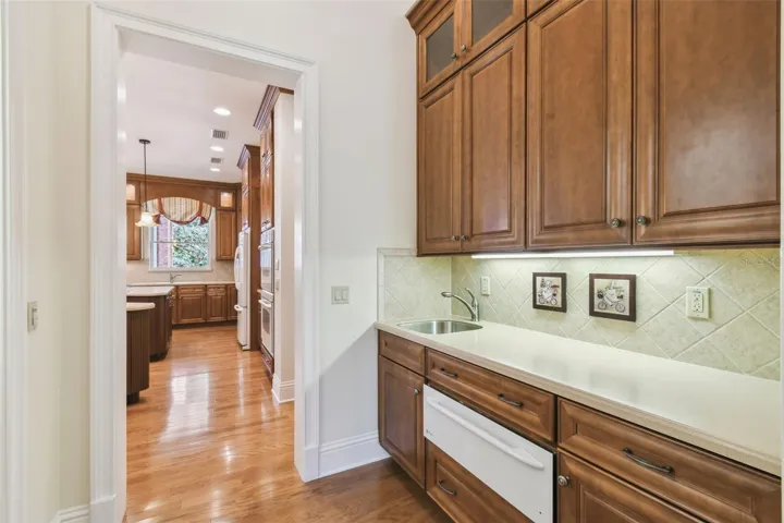 Gourmet chef’s kitchen showcases two expansive islands, three sinks, Corian countertops, custom cabinetry, a Bosch dishwasher, gas cooktop, and a separate ice maker. The adjacent butler’s pantry is perfect for entertaining, featuring a prep area, warming drawer, second refrigerator, and a spacious walk-in pantry.
