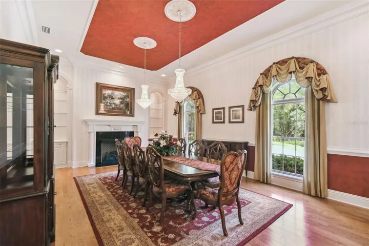 Formal dining room offers seating for 12, illuminated by two Swarovski chandeliers, and enhanced by a cozy gas fireplace and built-in shelving for elegant display or storage.