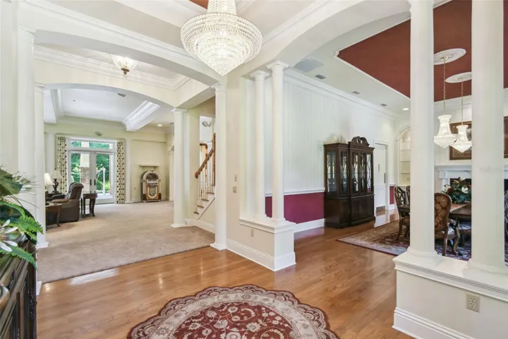 Elegant entryway features an elevated foyer adorned with a Swarovski chandelier (motorized for easy cleaning), rich hardwood floors, and a welcoming sense of grandeur.