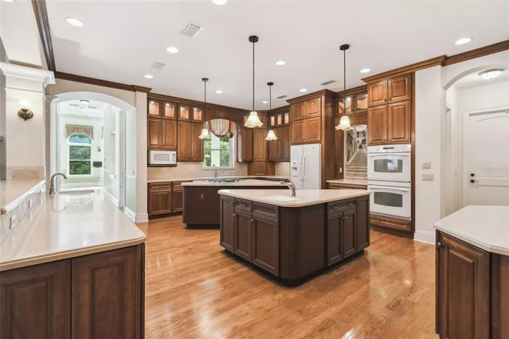 Gourmet chef’s kitchen showcases two expansive islands, three sinks, Corian countertops, custom cabinetry, a Bosch dishwasher, gas cooktop, and a separate ice maker. The adjacent butler’s pantry is perfect for entertaining, featuring a prep area, warming drawer, second refrigerator, and a spacious walk-in pantry.