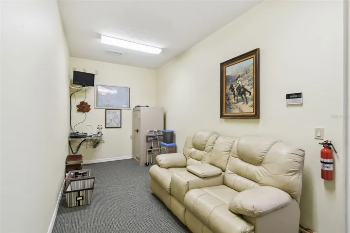Located in the garage is a secure, poured-concrete safe room with reinforced walls and roof, featuring a steel door with a cipher lock. The safe room is carpeted, air-conditioned, and comfortably outfitted with a couch and built-in shelving for storage.